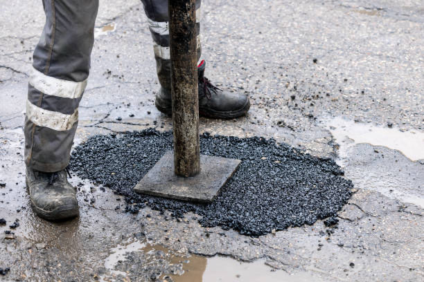 Worker repairing a pothole with fresh asphalt